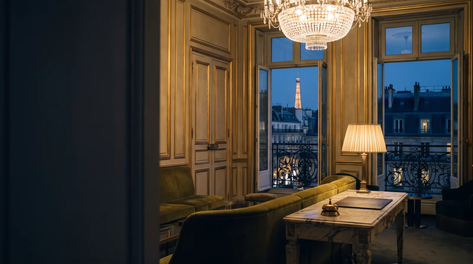 A quiet luxury hotel lobby at night with a brass bell on the reception desk