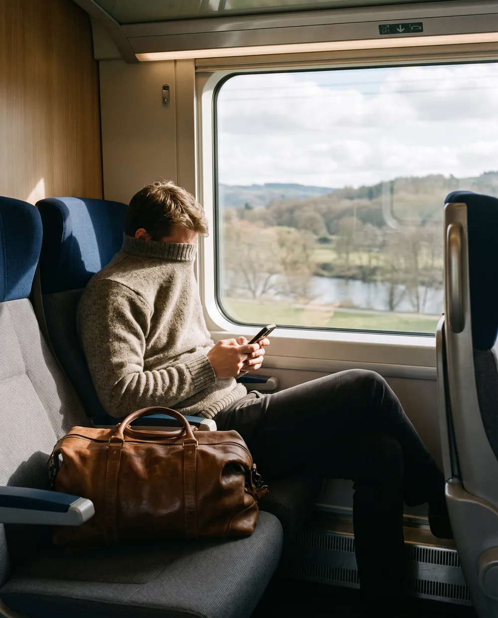 A traveller writing a message on a phone on a train